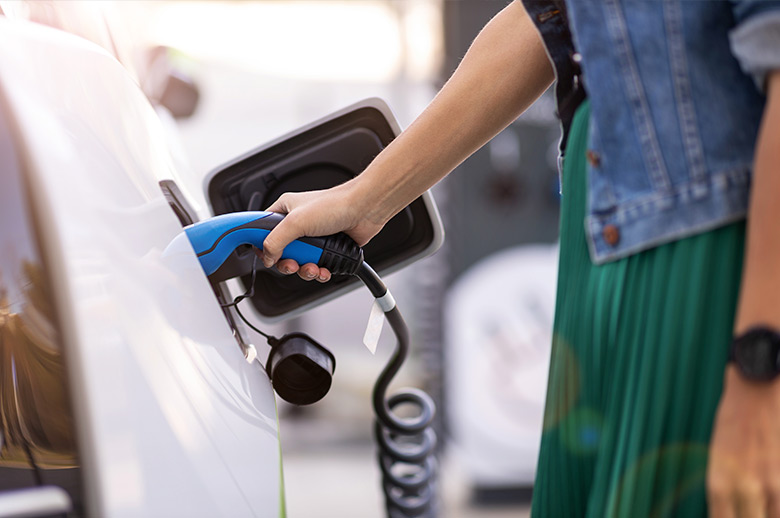 Femme rechargeant sa voiture à une borne électrique.